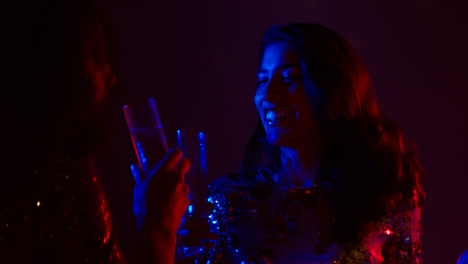 Close-Up-Of-Two-Women-In-Nightclub-Bar-Or-Disco-Dancing-And-Drinking-Alcohol-With-Sparkling-Lights